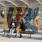 a couple of women sitting on a bench in front of a wall with graffiti